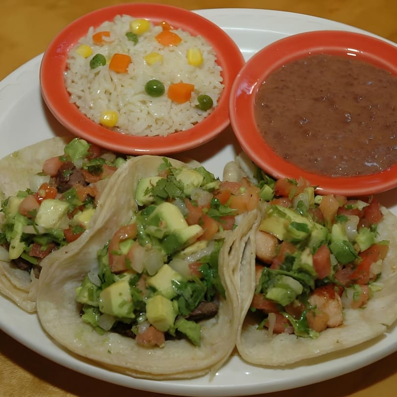 Three Salvadoran tacos with avocado, tomato, and cilantro, served with rice and refried beans.